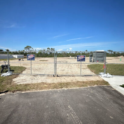 Double swing gate setup with temporary fencing at a cleared construction site in Florida, featuring American Fence & Security signage.